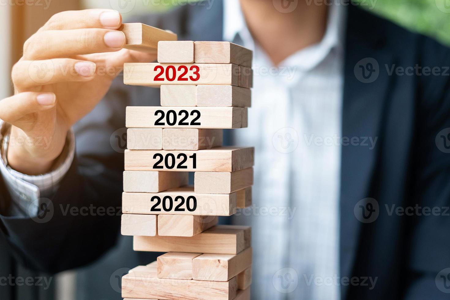 Objectifs de l'année 2023, planification d'entreprise, gestion des risques, concepts de solution et de stratégie. main d'homme d'affaires plaçant ou tirant un bloc de bois sur la tour photo