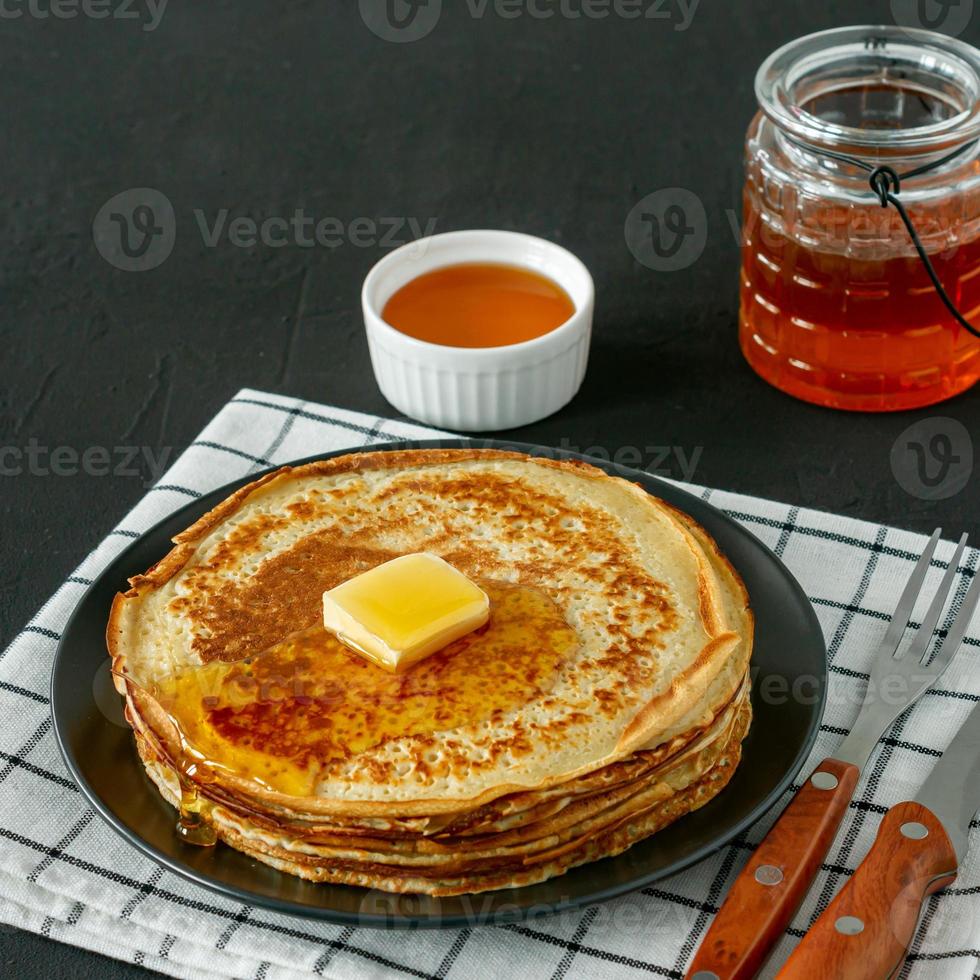 crêpes servies avec sirop de miel et beurre sur une assiette sombre. crêpes traditionnelles pour la semaine des crêpes ou le mardi gras. photo