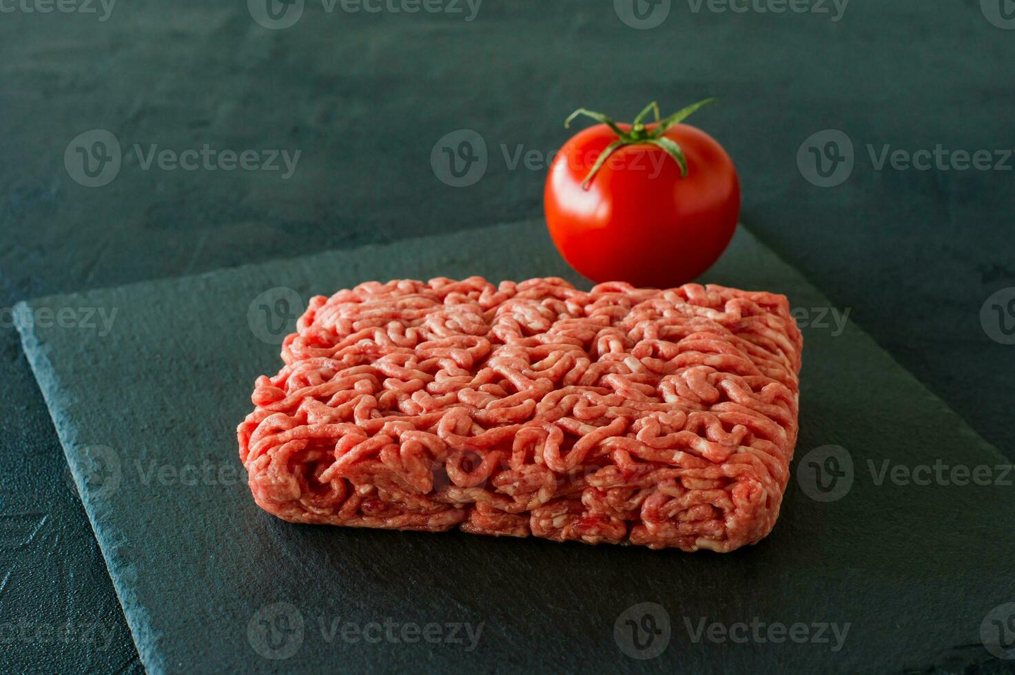 viande de boeuf hachée crue sur une ardoise à la tomate. photo
