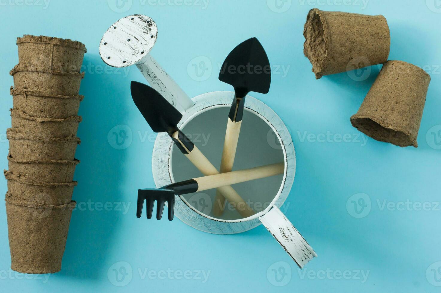 outils pour jardiner à la maison. outils de jardin pour plantes en pot - pelle, arrosoir et râteau. vue de dessus. flatlay sur fond bleu photo