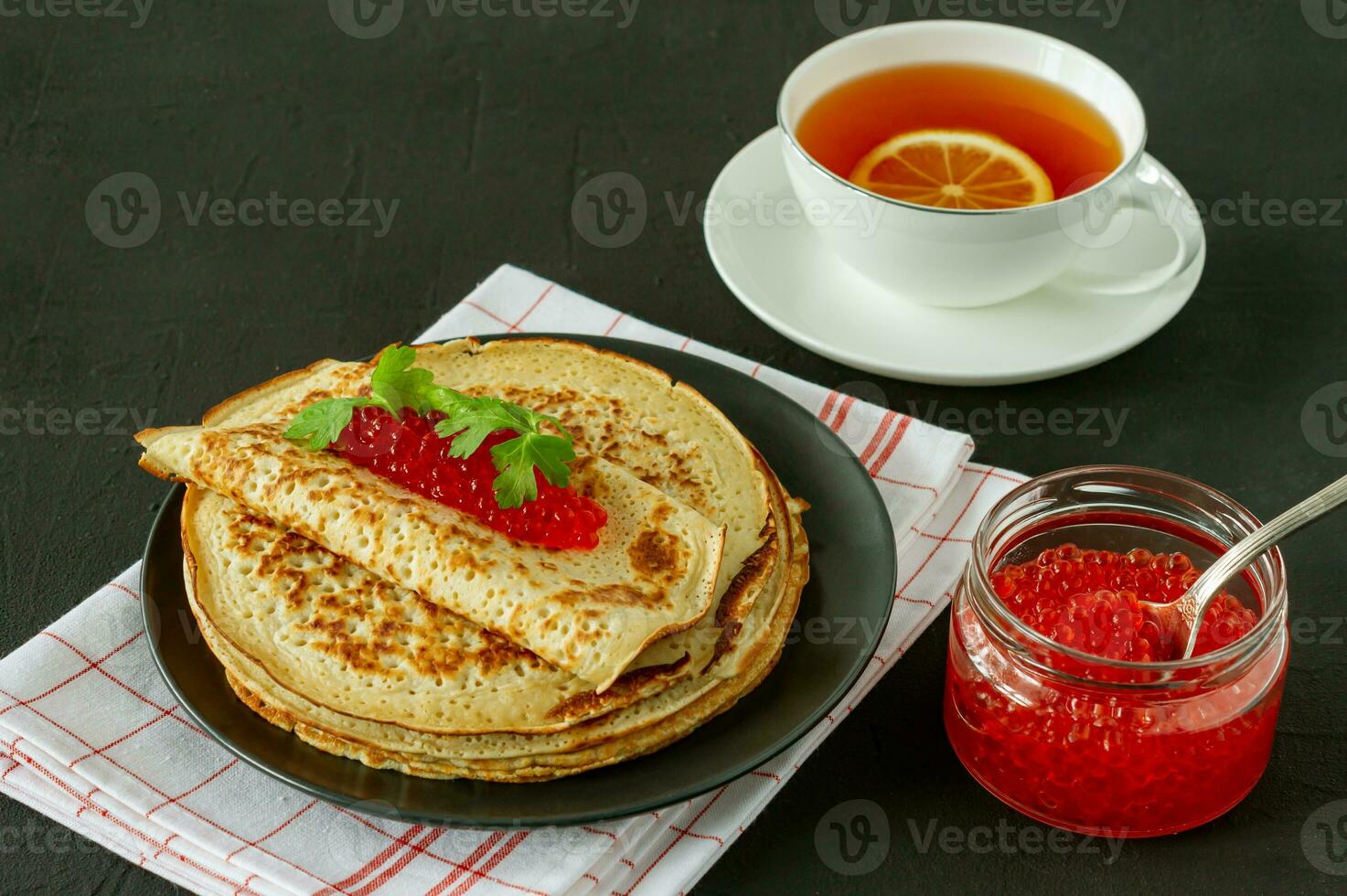 Blini de crêpes russes traditionnelles empilées dans une assiette avec du caviar rouge et du thé au citron chaud sur fond de bois. maslenitsa repas traditionnel du festival russe. cuisine russe, cuisine russe. photo