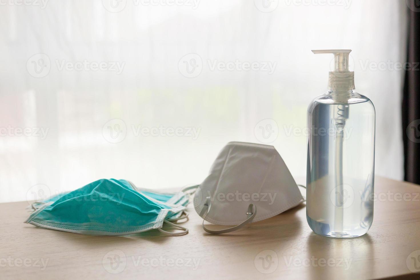 masque facial médical avec gel désinfectant à l'alcool lavage des mains sur table en bois pour le concept de prévention du coronavirus covid-19 photo