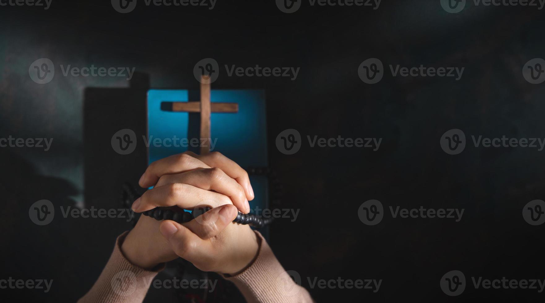 concept de spiritualité, de religion et d'espoir. personne priant par la sainte bible et croix sur le bureau. symbole d'humilité, de supplication, de croyance et de foi pour le peuple chrétien. vue de dessus photo