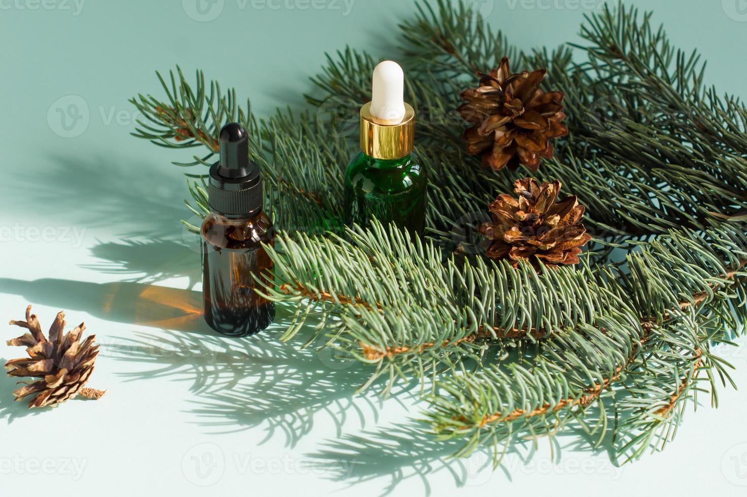 deux flacons compte-gouttes d'huile essentielle et de branches de sapin. concept d'aromathérapie et de spa de noël. photo