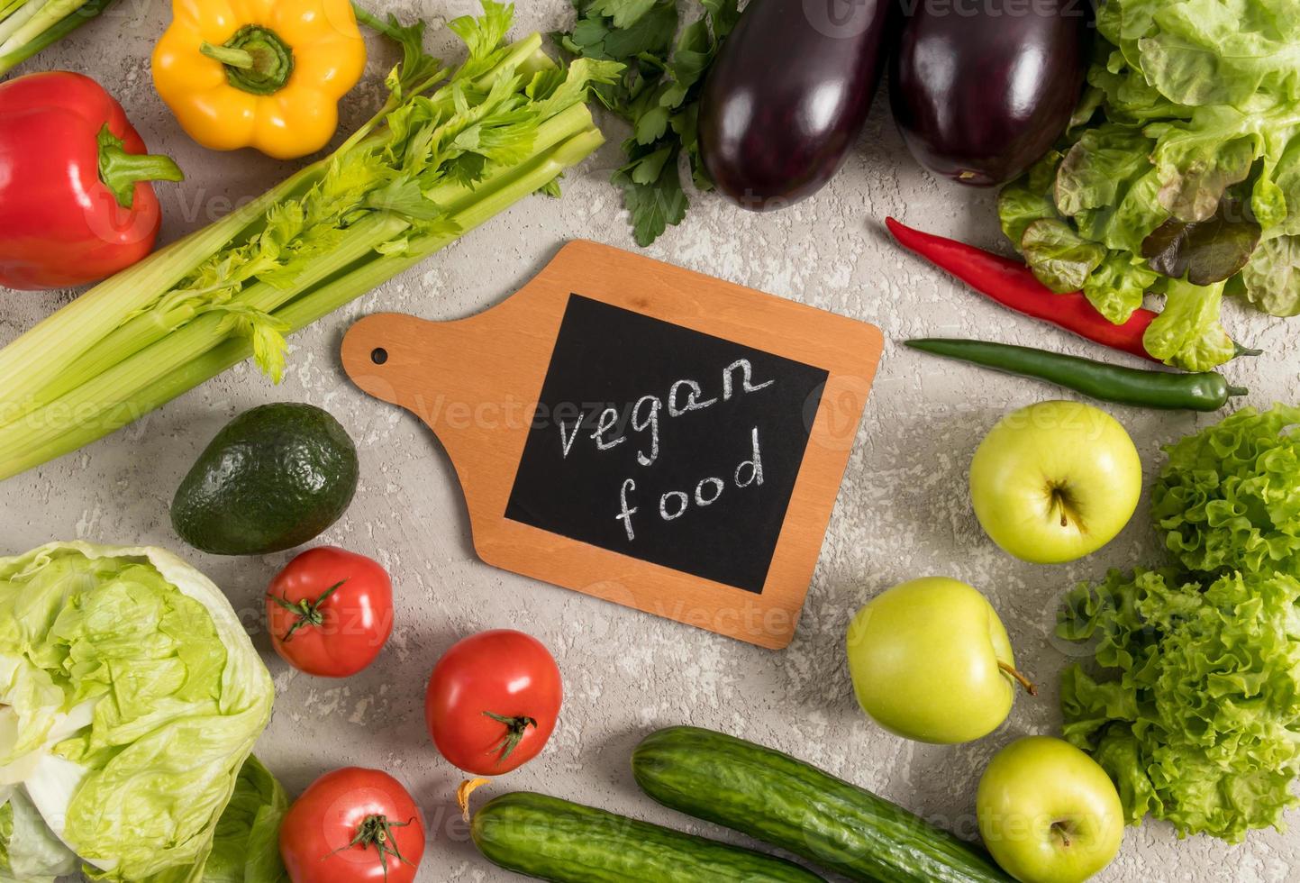 un cadre de produits biologiques sur fond gris au centre avec une planche de cuisine - nourriture végétalienne. le concept d'une alimentation saine. photo