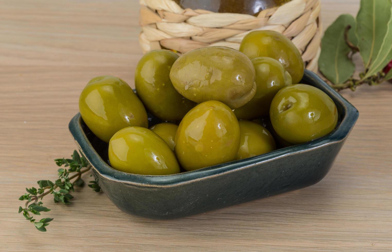 olives vertes dans un bol sur fond de bois photo