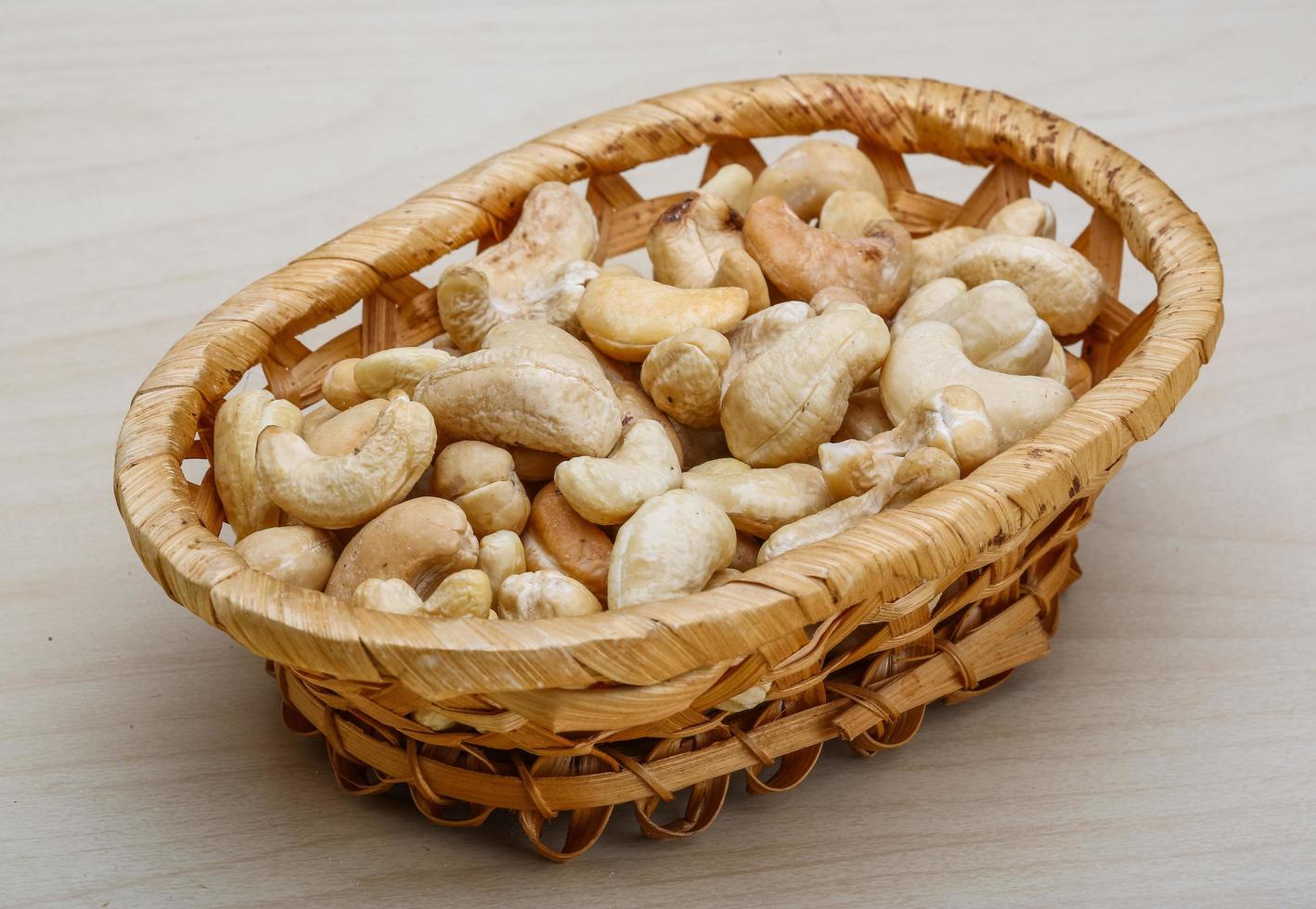 Noix de cajou dans un panier sur fond de bois photo