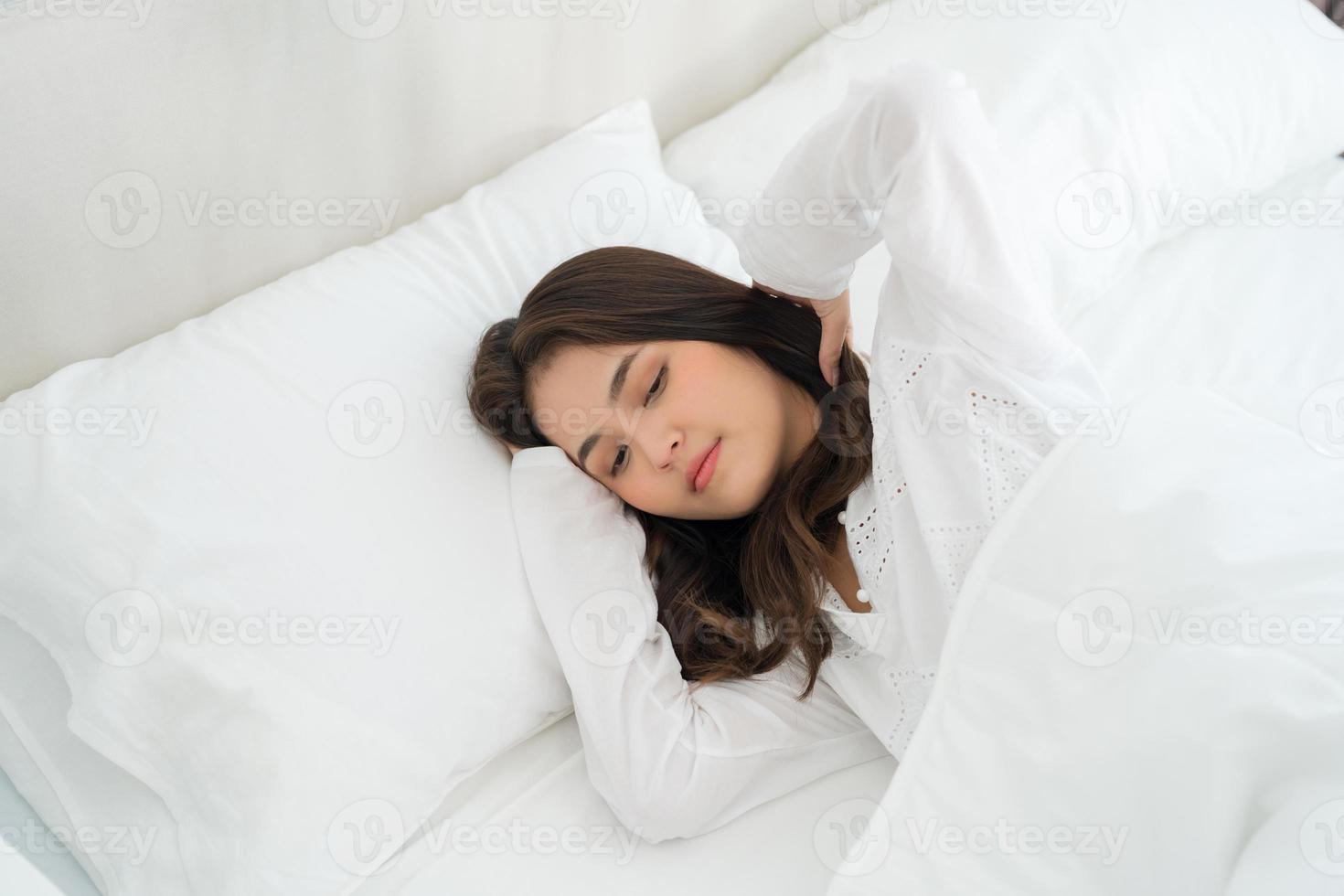 fille allongée dans son lit malade souffre d'insomnie mal de tête anxiété, tenant la tête photo