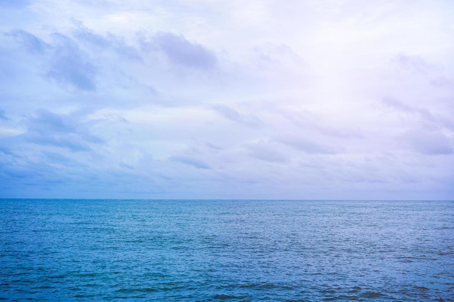 vide de nuages blancs sur un ciel bleu au-dessus d'une mer calme avec espace de copie pour fond de bannière ou de papier peint. concept de paysage marin photo