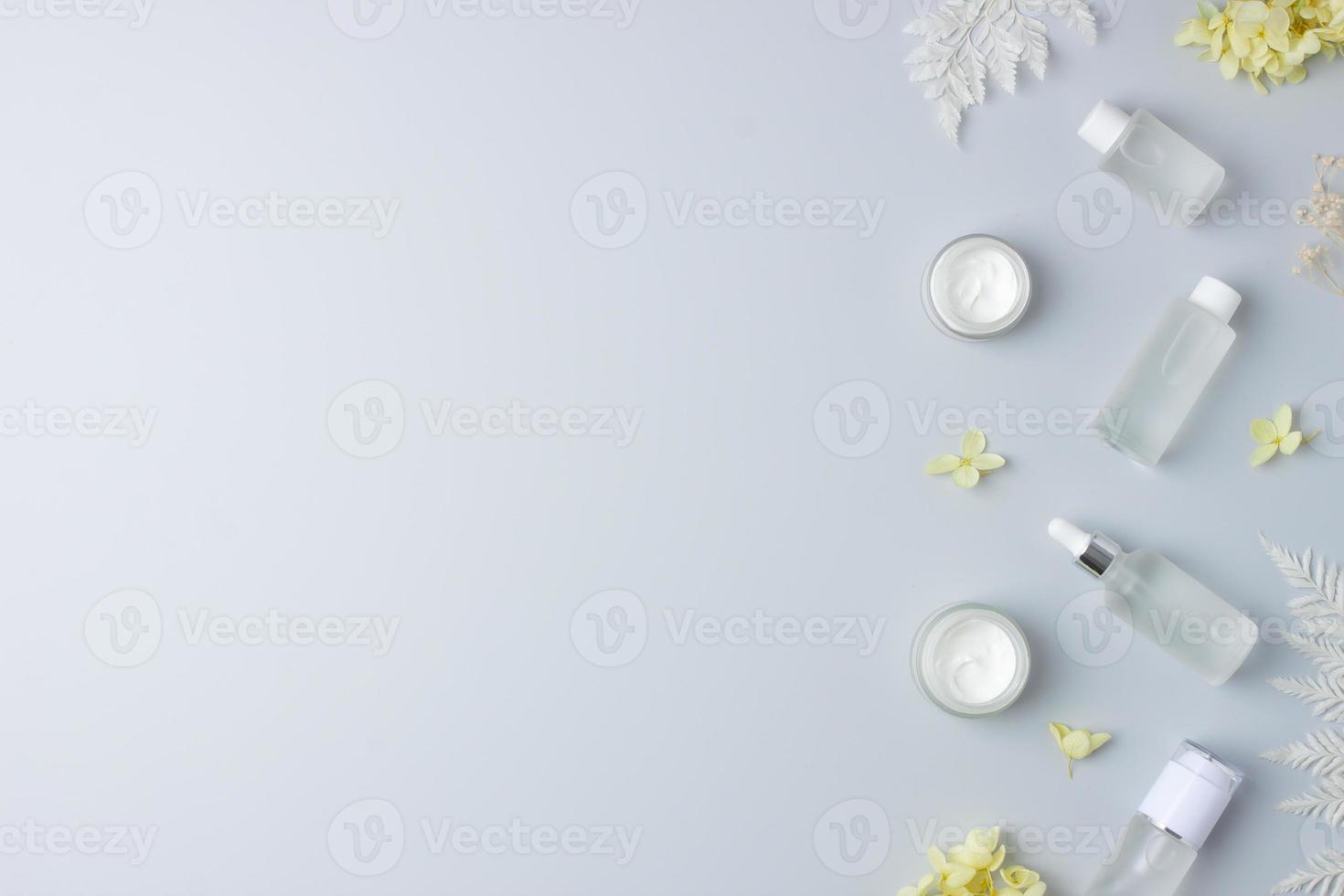 produits cosmétiques de soins de la peau avec des fleurs sur fond gris. mise à plat, espace de copie photo