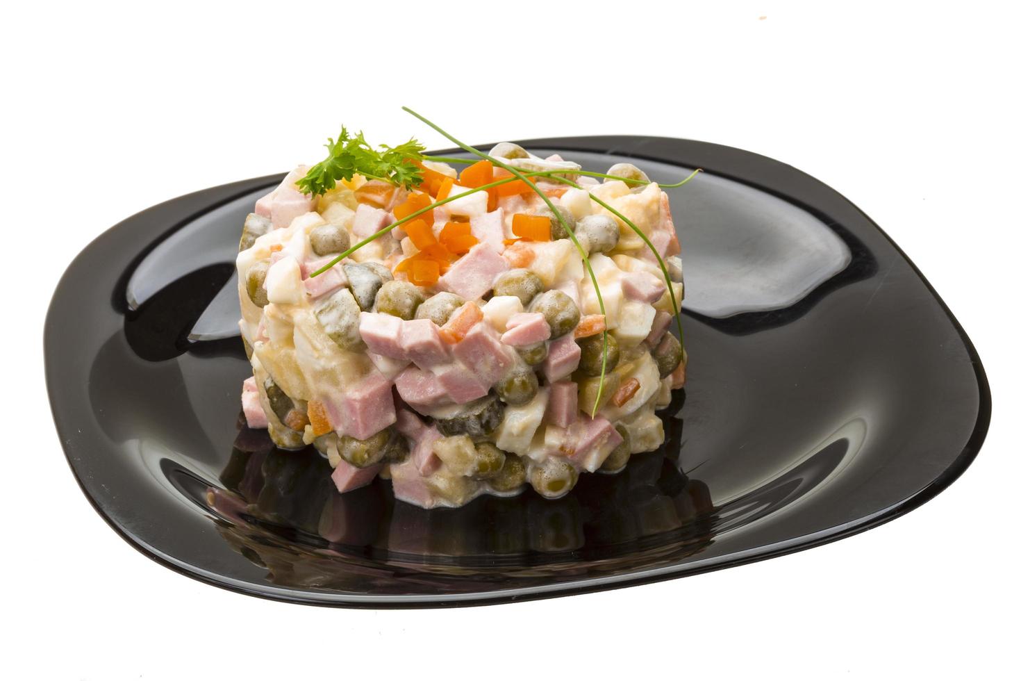 Salade russe sur l'assiette et fond blanc photo