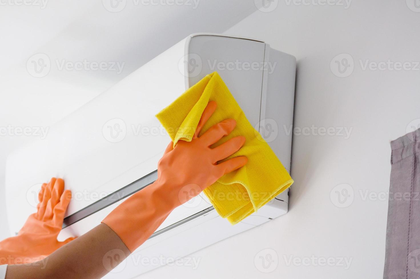 homme asiatique nettoyant le climatiseur avec un chiffon en microfibre photo