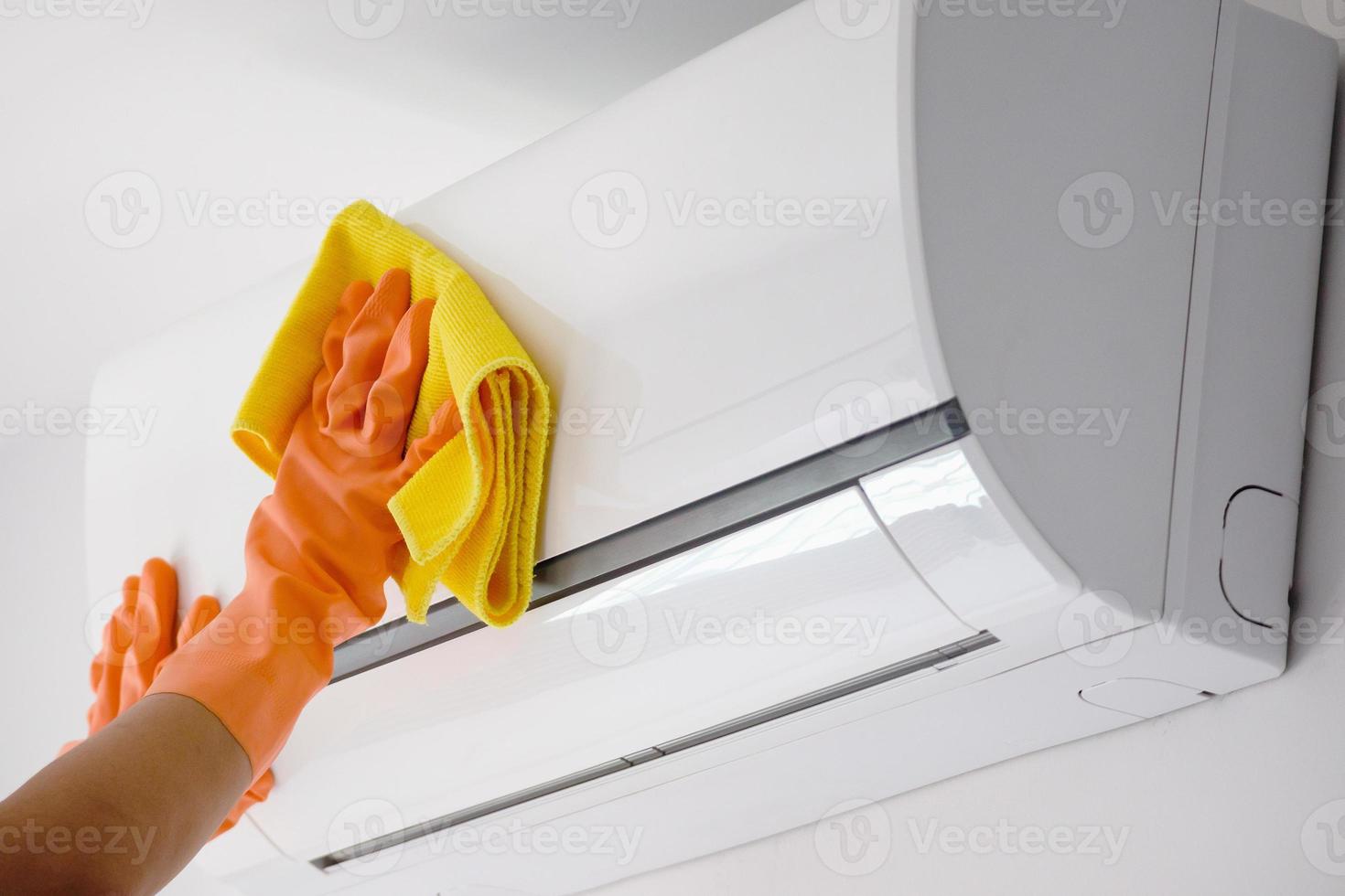 homme asiatique nettoyant le climatiseur avec un chiffon en microfibre photo