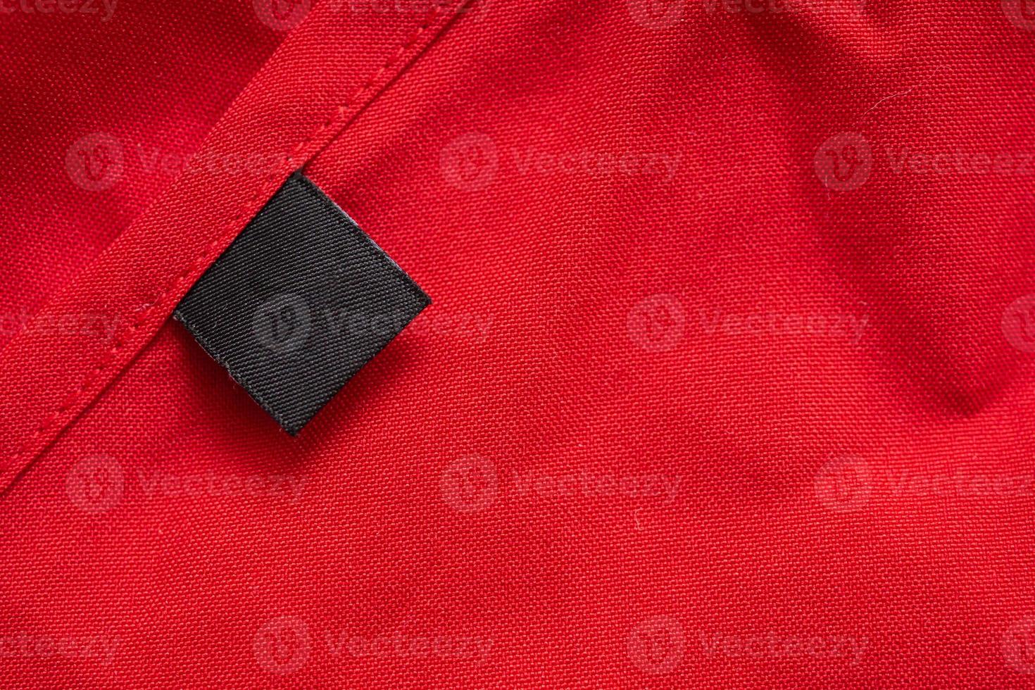 étiquette de vêtements de soin de lessive noire vierge sur la texture de tissu de couleur rouge photo