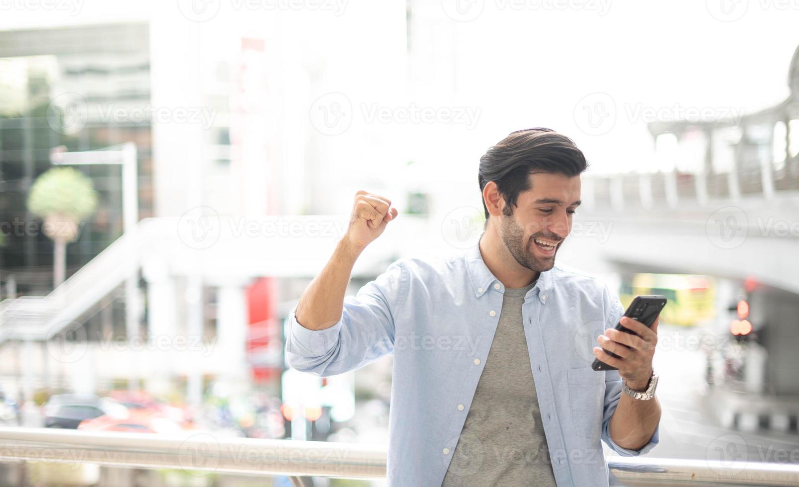 le jeune homme utilisant un smartphone pour obtenir la bonne nouvelle. l'homme portant un tissu décontracté et se sentant heureux et relaxant. photo