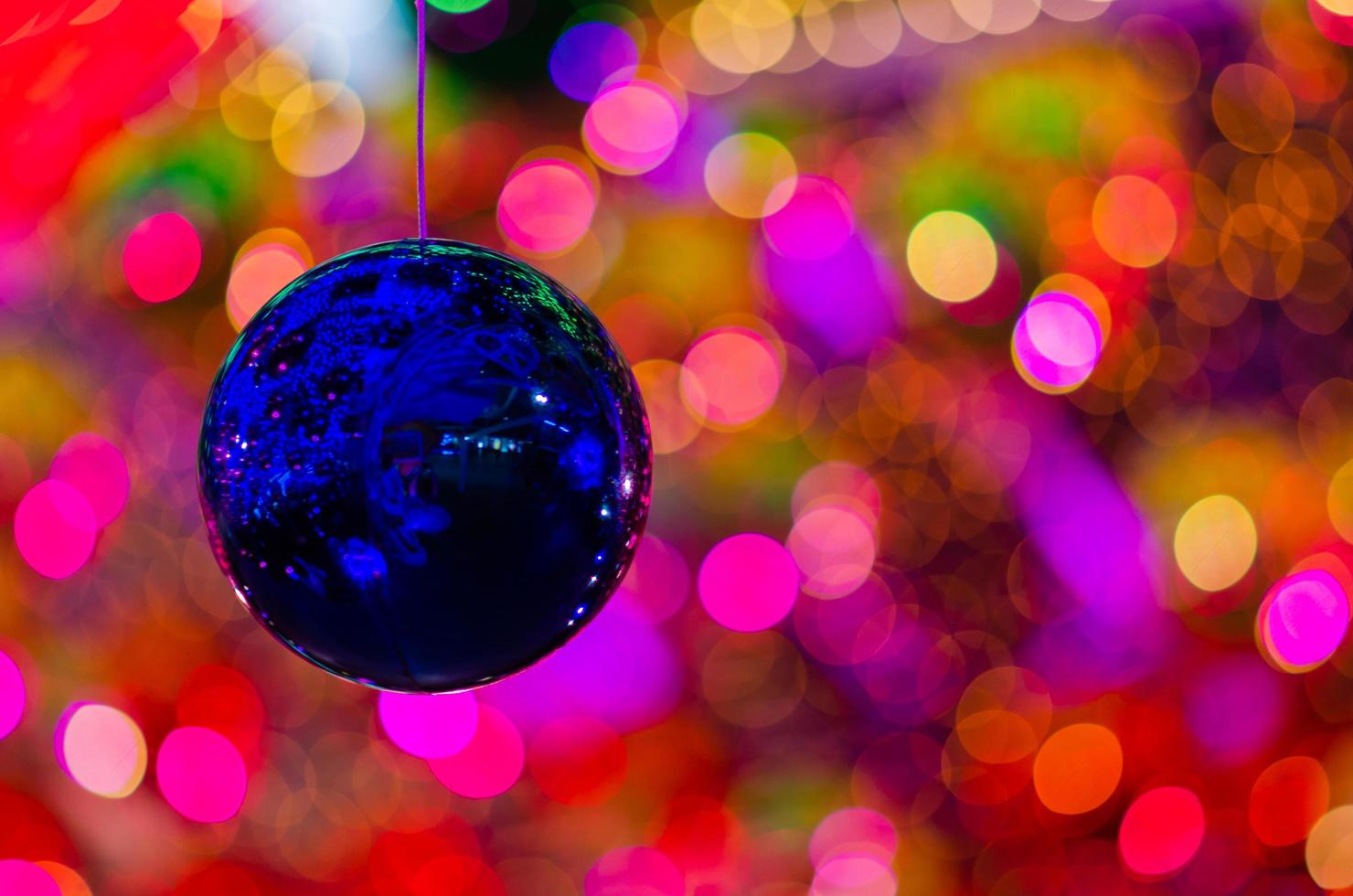 boule bleue suspendue à décorer pour les vacances de noël avec un bokeh coloré de la lumière et d'autres boules. photo