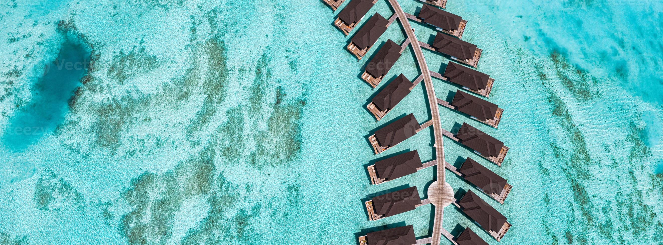 paysage aérien parfait, complexe tropical de luxe avec villas sur l'eau. belle plage de l'île, palmiers, ciel ensoleillé. vue imprenable sur les yeux d'oiseau aux maldives, côte paradisiaque. tourisme exotique, relax nature mer photo