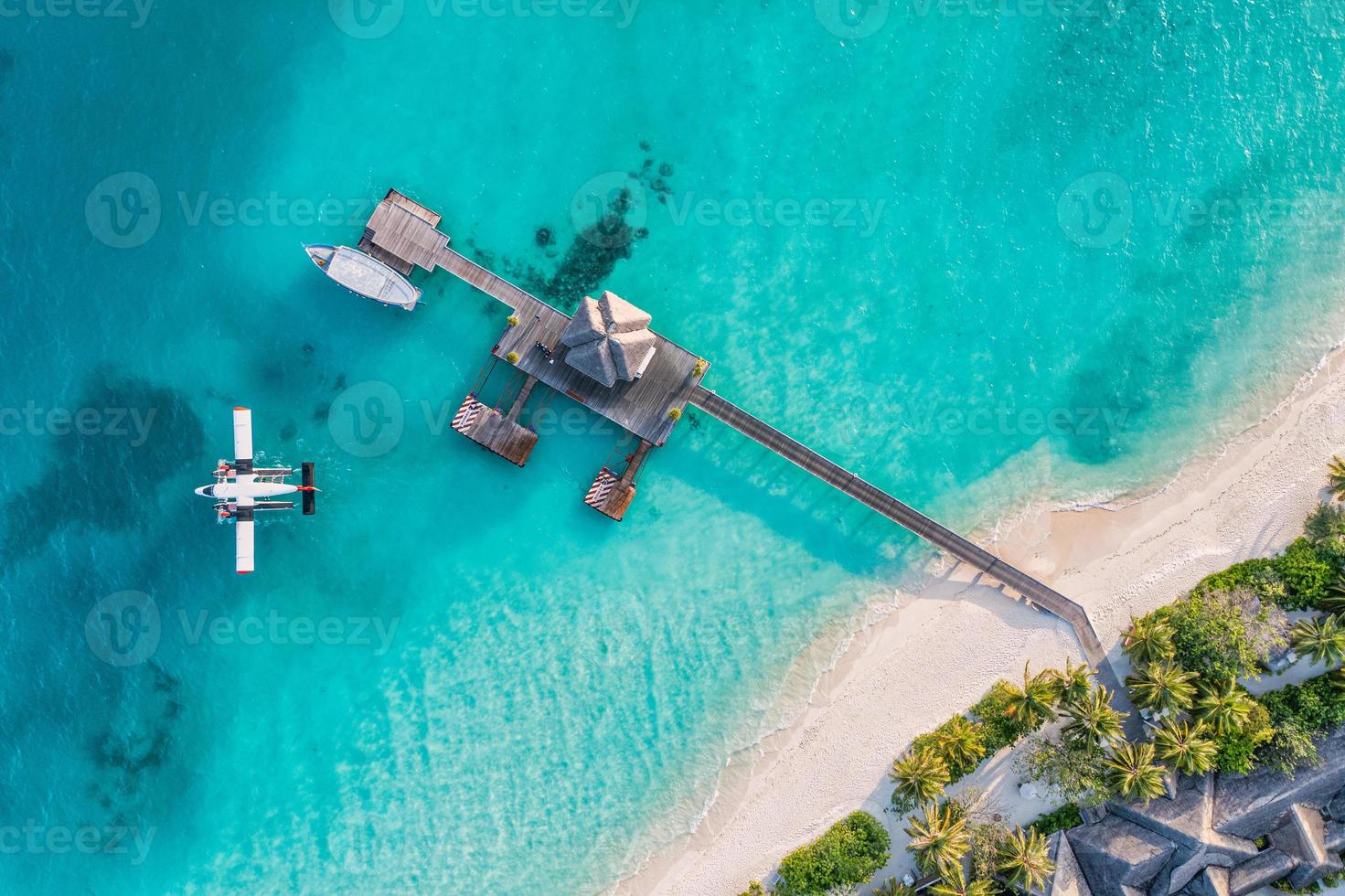 belle vue aérienne de la côte des maldives, vue de dessus d'hydravion de villa de jetée, dhoni de bateau en bois et plage tropicale. palmiers sable blanc, mer. concept de voyage et de vacances de luxe. magnifique paysage aérien photo