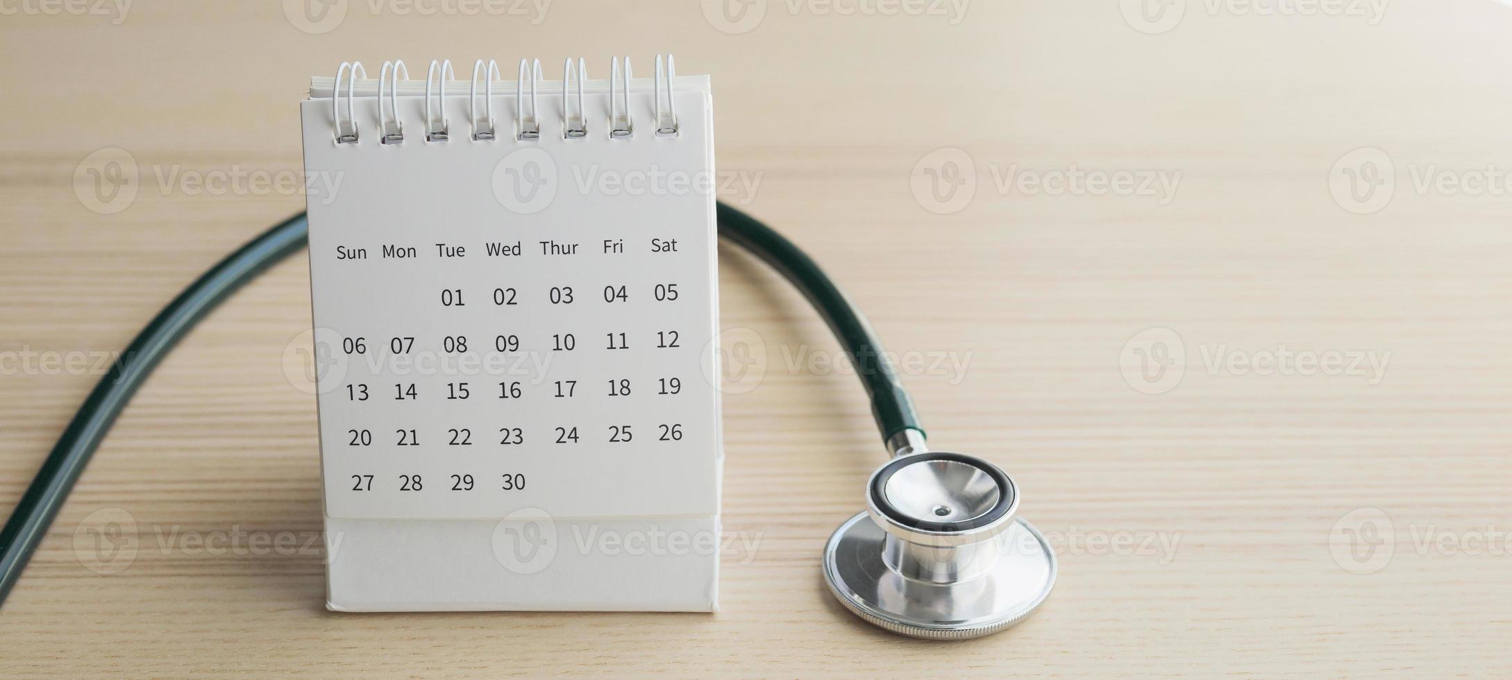 stéthoscope avec date de page de calendrier sur fond de table en bois rendez-vous chez le médecin concept médical photo