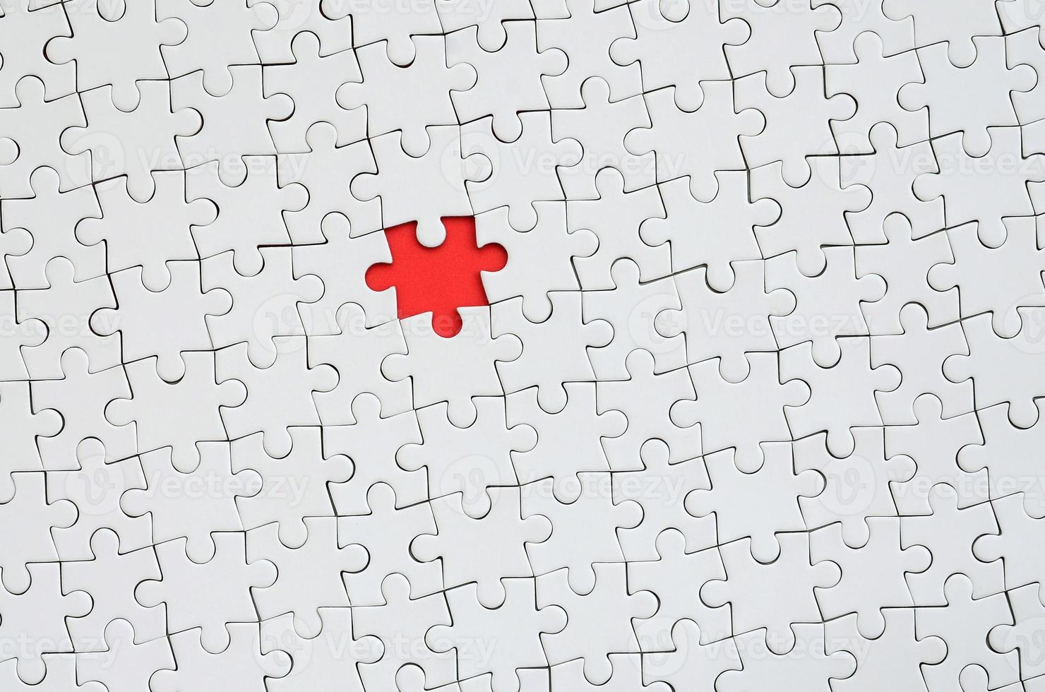 la texture d'un puzzle blanc à l'état assemblé avec un élément manquant formant un espace rouge photo