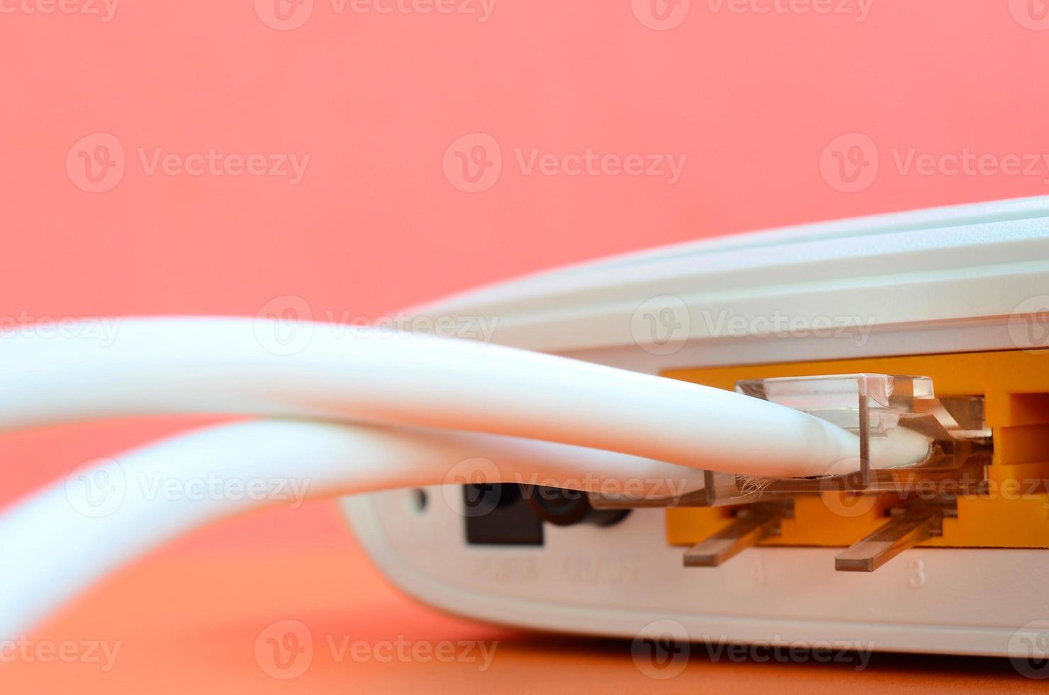 les fiches du câble Internet sont connectées au routeur Internet, qui se trouve sur un fond orange vif. éléments nécessaires à la connexion Internet photo