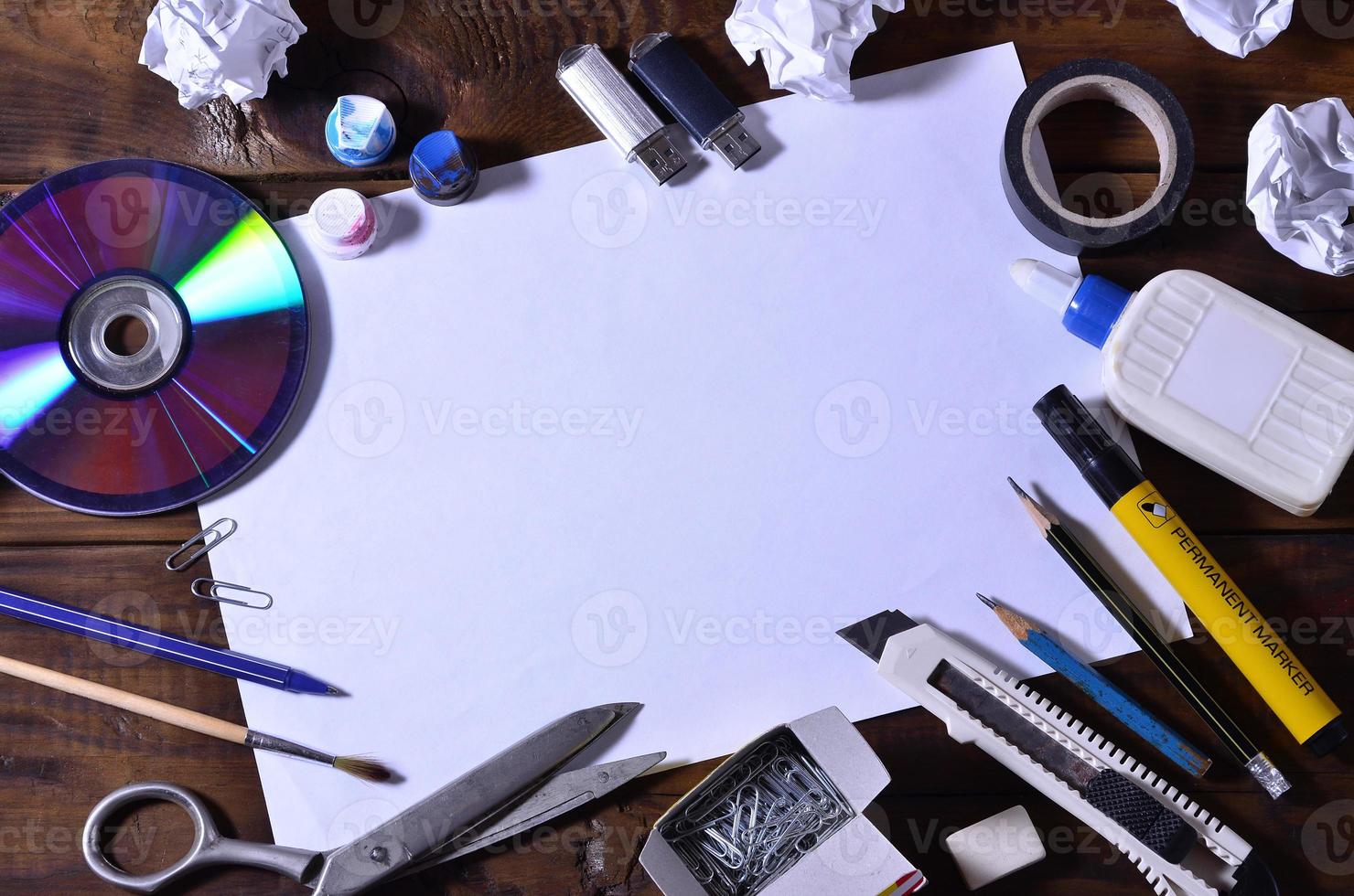 une école ou un bureau nature morte avec une feuille de papier vierge blanche et de nombreuses fournitures de bureau. les fournitures scolaires se trouvent sur un fond en bois marron. place pour le texte photo