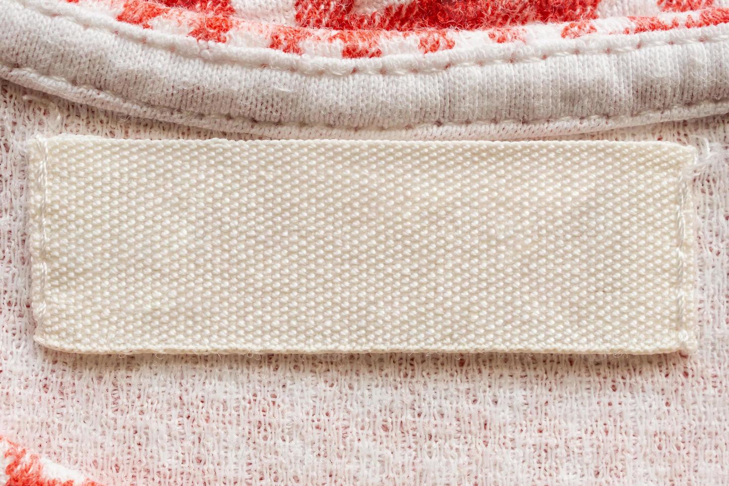 Étiquette de vêtements de soin de lessive blanc vierge sur fond de chemise en coton photo