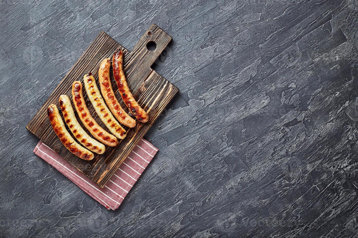 savoureuses saucisses de porc grillées aux épices et herbes sur une planche à découper en bois photo