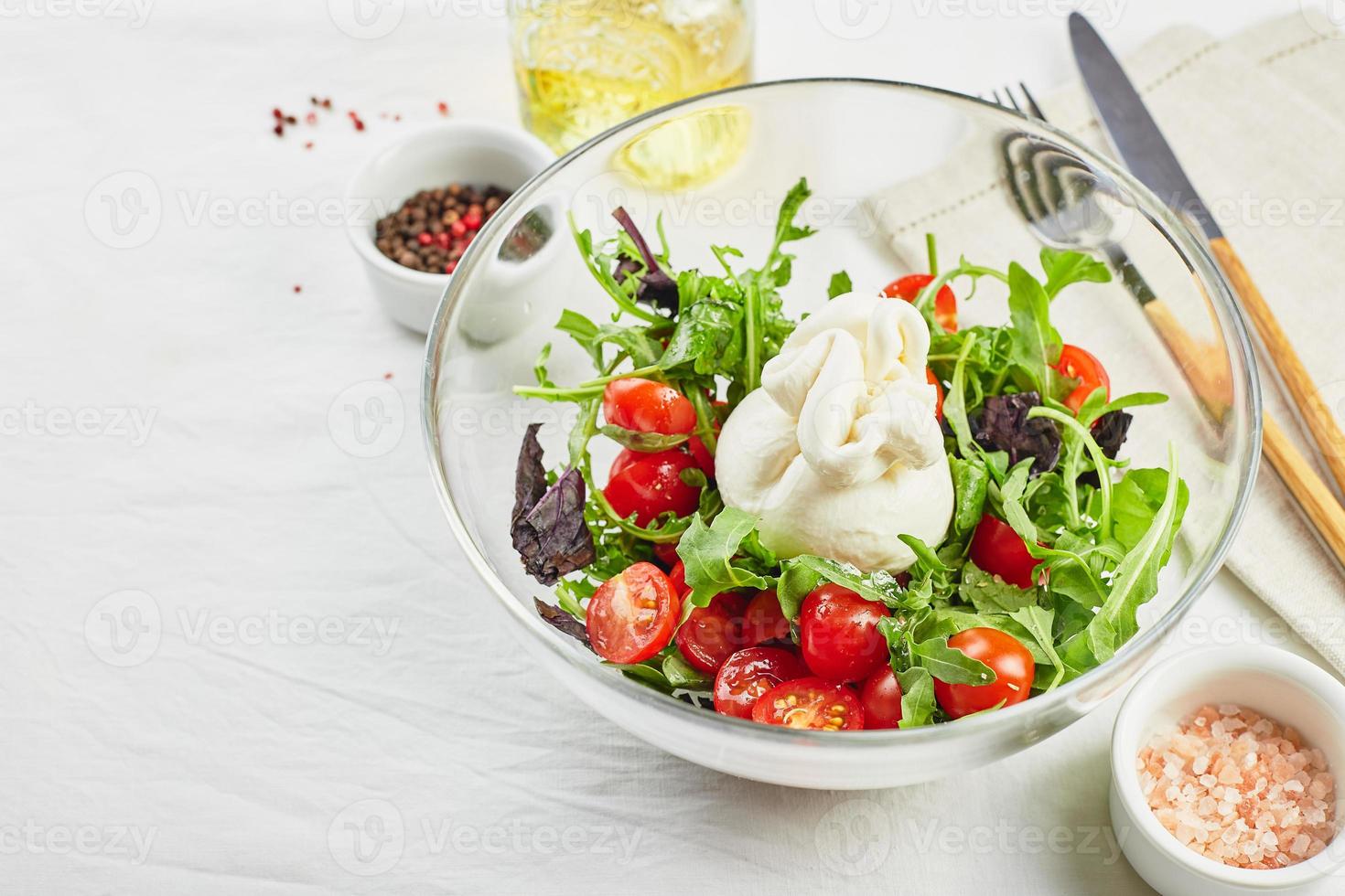 burrata, fromage frais italien à base de crème et de lait de bufflonne ou de vache, avec salade de tomates, roquette et basilic rouge photo