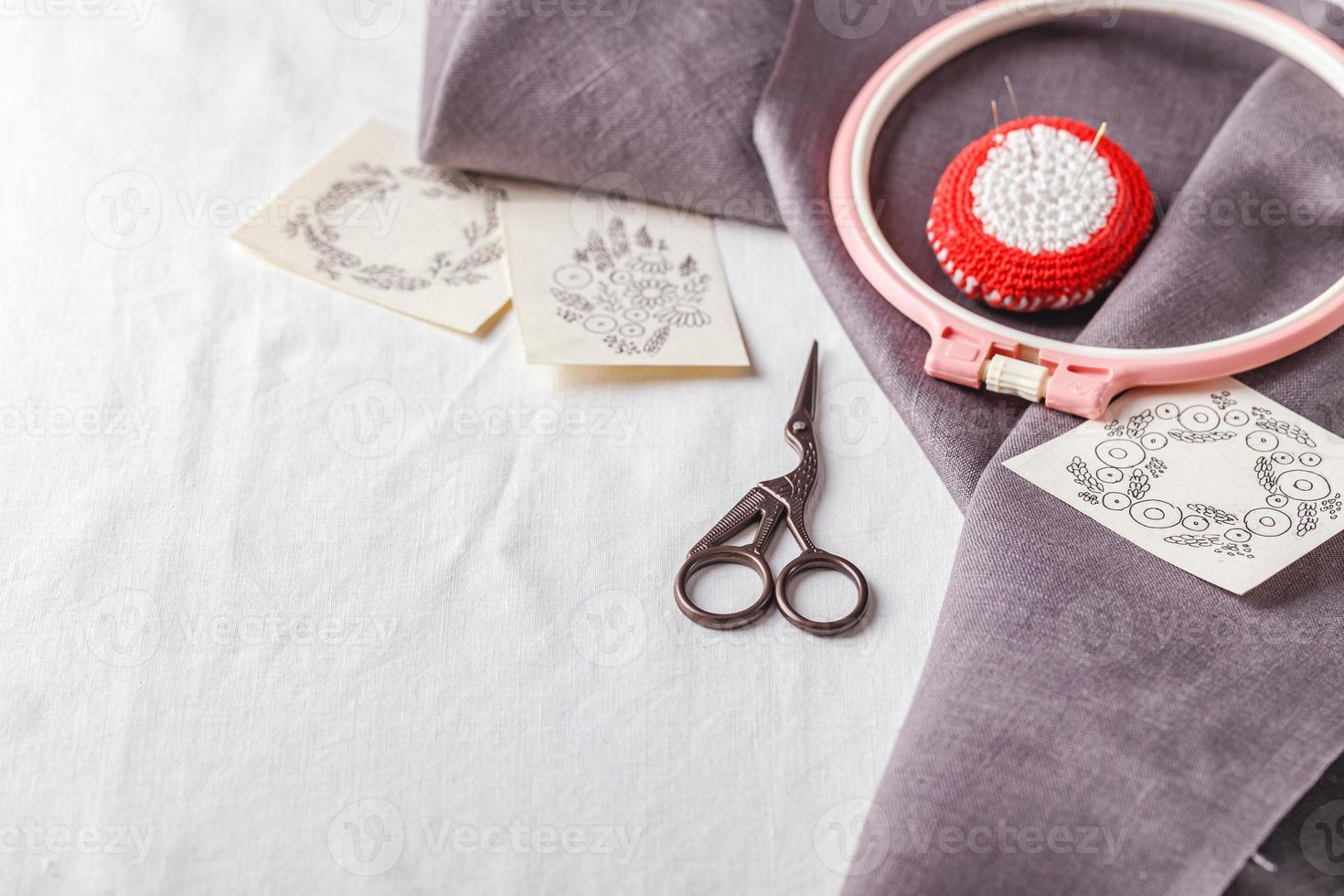 ensemble de broderie. toile de lin, motifs de broderie, cercle à broder et aiguilles. photo