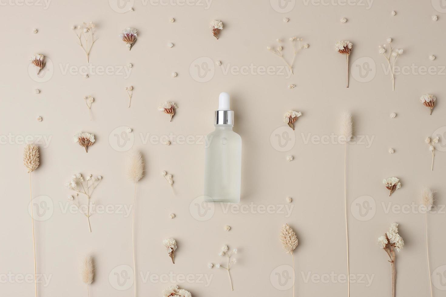 bouteille cosmétique avec des fleurs sur fond beige pastel. mise à plat photo