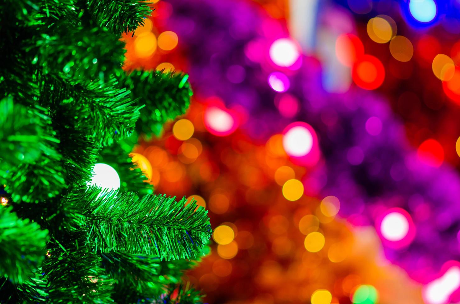 mise au point sélective sur l'arbre de noël vert avec ampoule et mise au point floue des arbres de noël colorés. photo