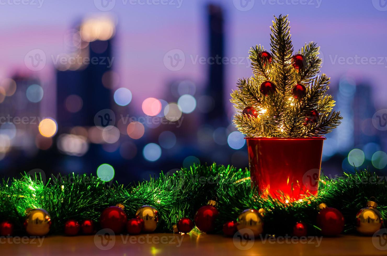 arbre de noël décoré d'ornements de babiole et de lumières sur la table avec fond de lumières colorées de bokeh de ville. photo