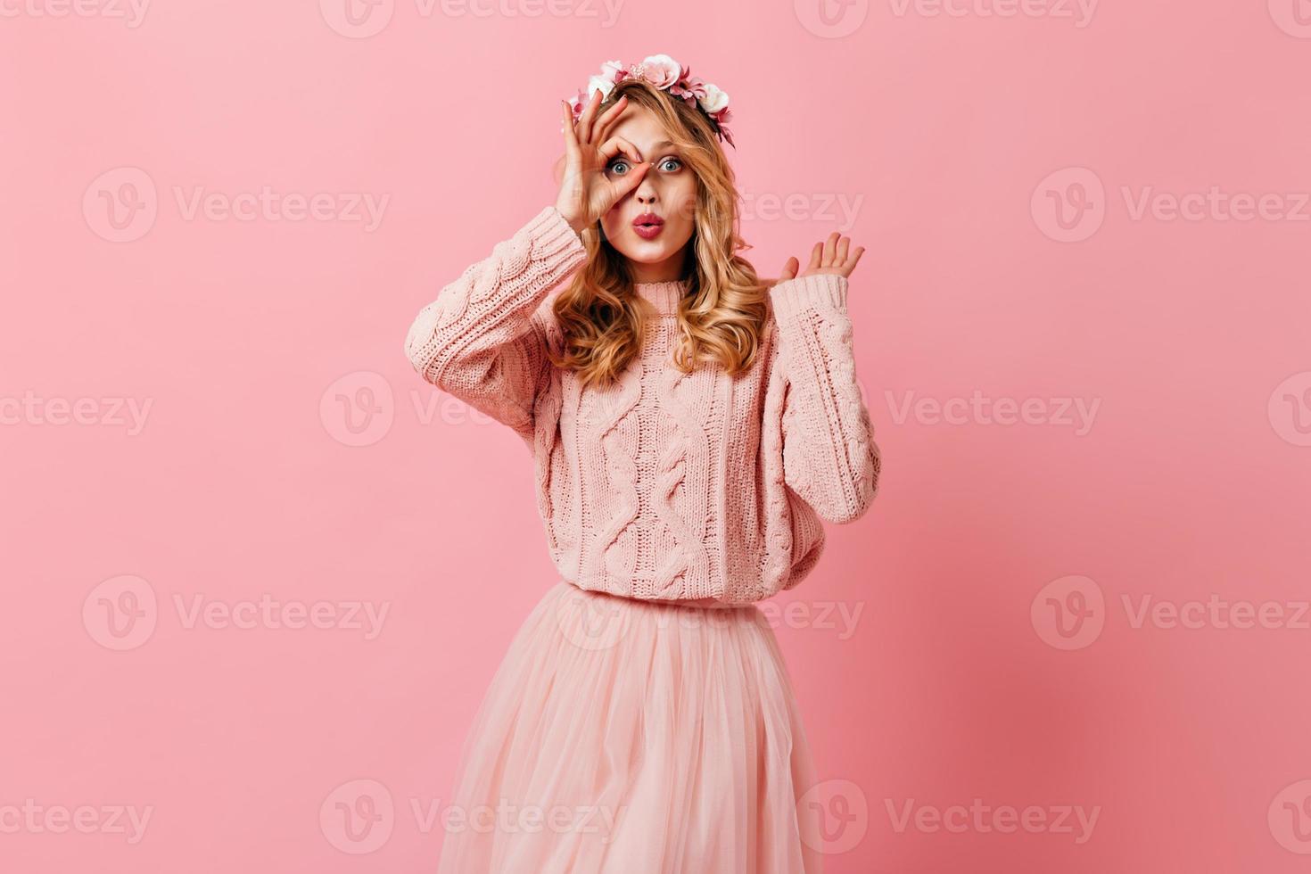femme en jupe moelleuse rose et pull tricoté montre signe ok. fille avec couronne de roses posant sur est photo