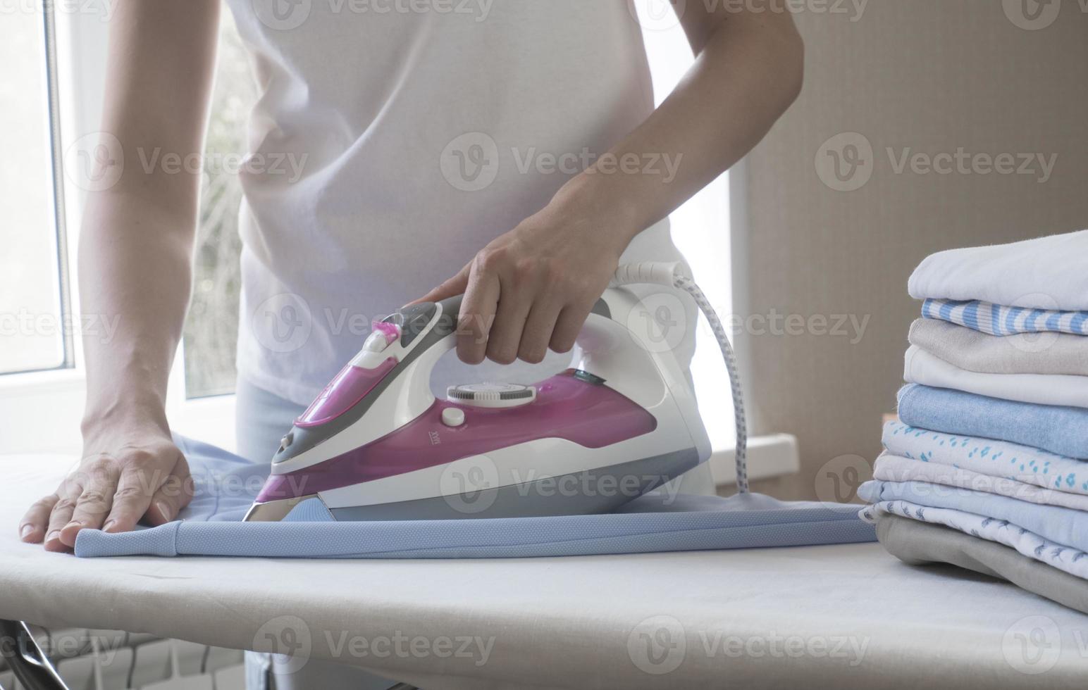 gros plan main de femme repassage des vêtements jupe bleue sur une planche à repasser. photo