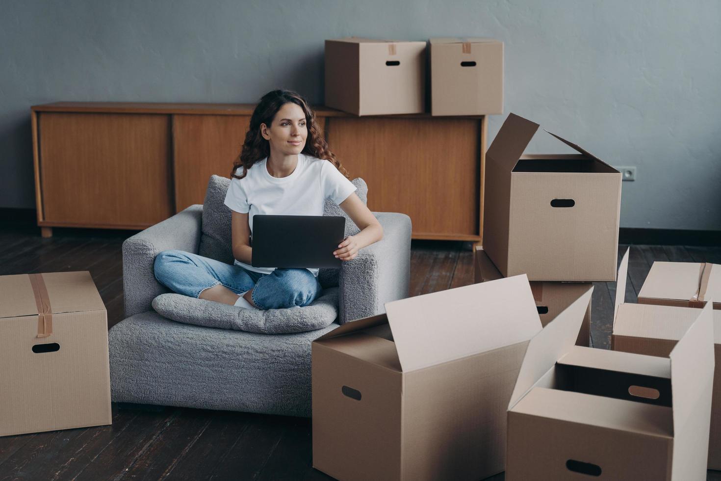 fille heureuse assise devant un ordinateur portable avec des boîtes en carton, rêvant d'une nouvelle maison, déménagement photo