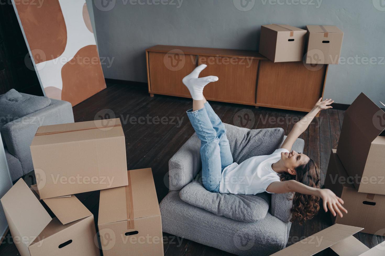 une femme excitée célèbre son déménagement dans une nouvelle maison, se réjouissant entourée de boîtes en carton le jour du déménagement photo