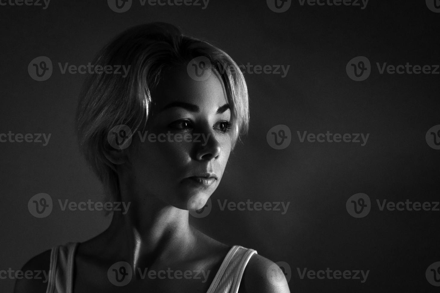 portrait féminin en gros plan regarde ailleurs, photo noir et blanc sombre