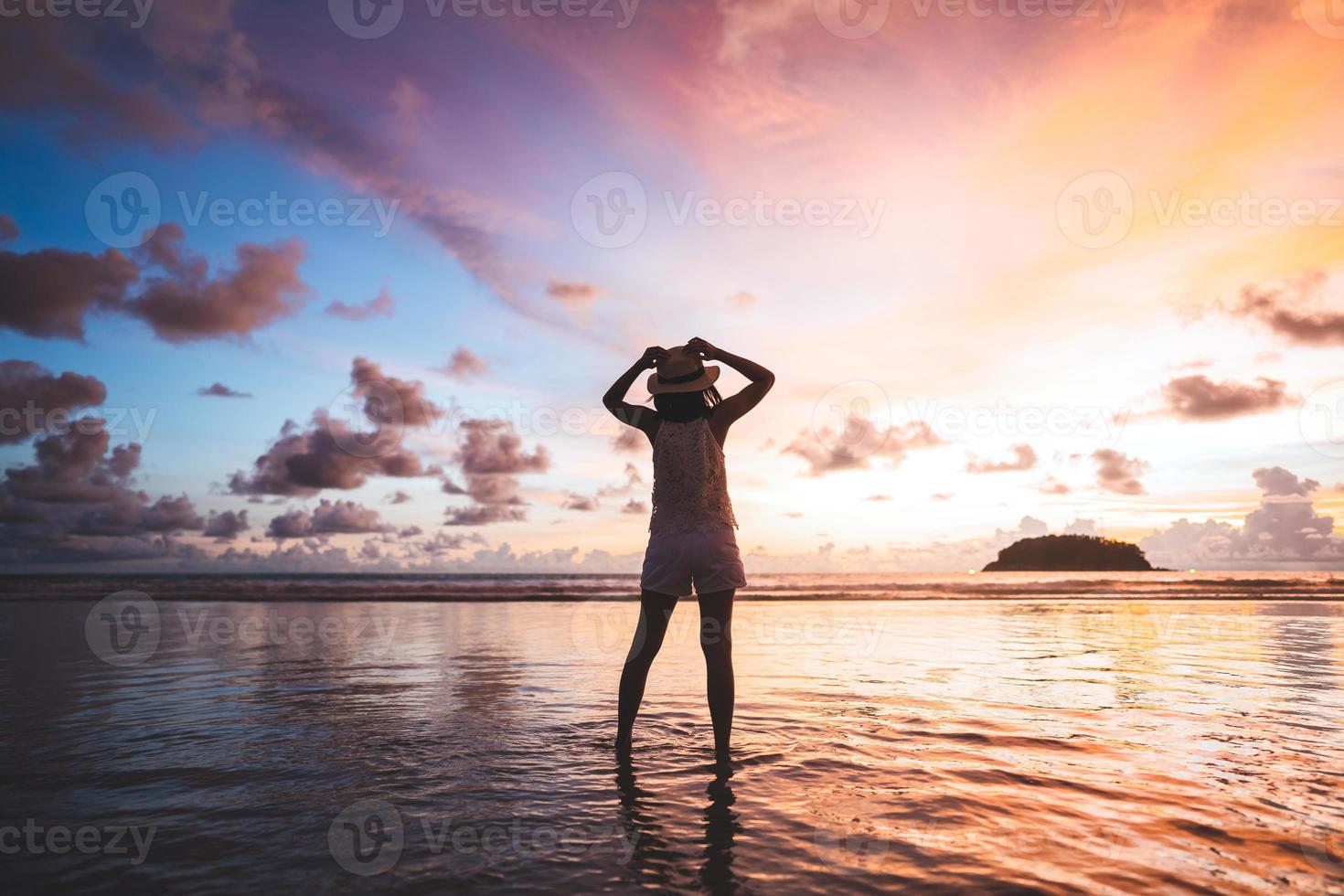 vue arrière d'une femme de voyage adulte se détendre sur le sable de la plage avec ciel coucher de soleil crépusculaire photo