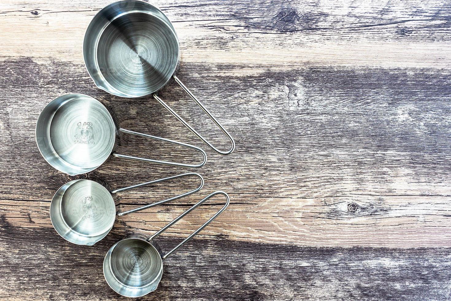 ensemble de tasses à mesurer en acier inoxydable avec une poignée sur une table en bois en vue de dessus photo