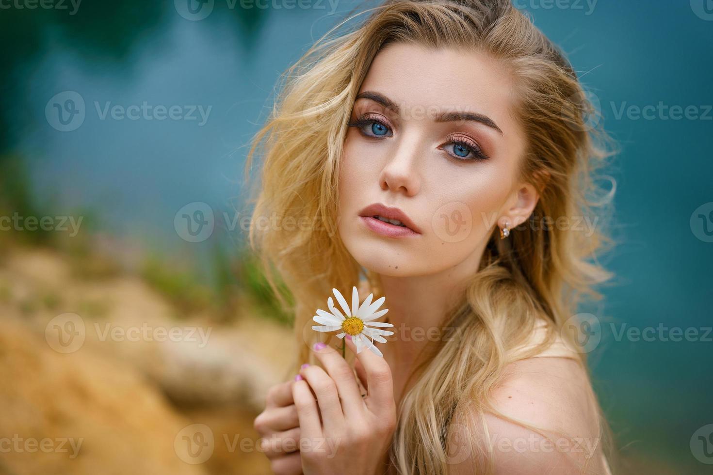 portrait d'une belle fille avec une marguerite dans les mains, beau maquillage photo