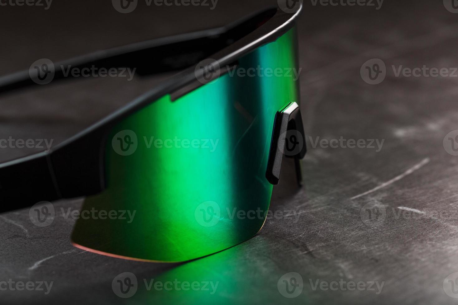 lunettes de sport avec une lentille verte en miroir sur un fond texturé noir. photo