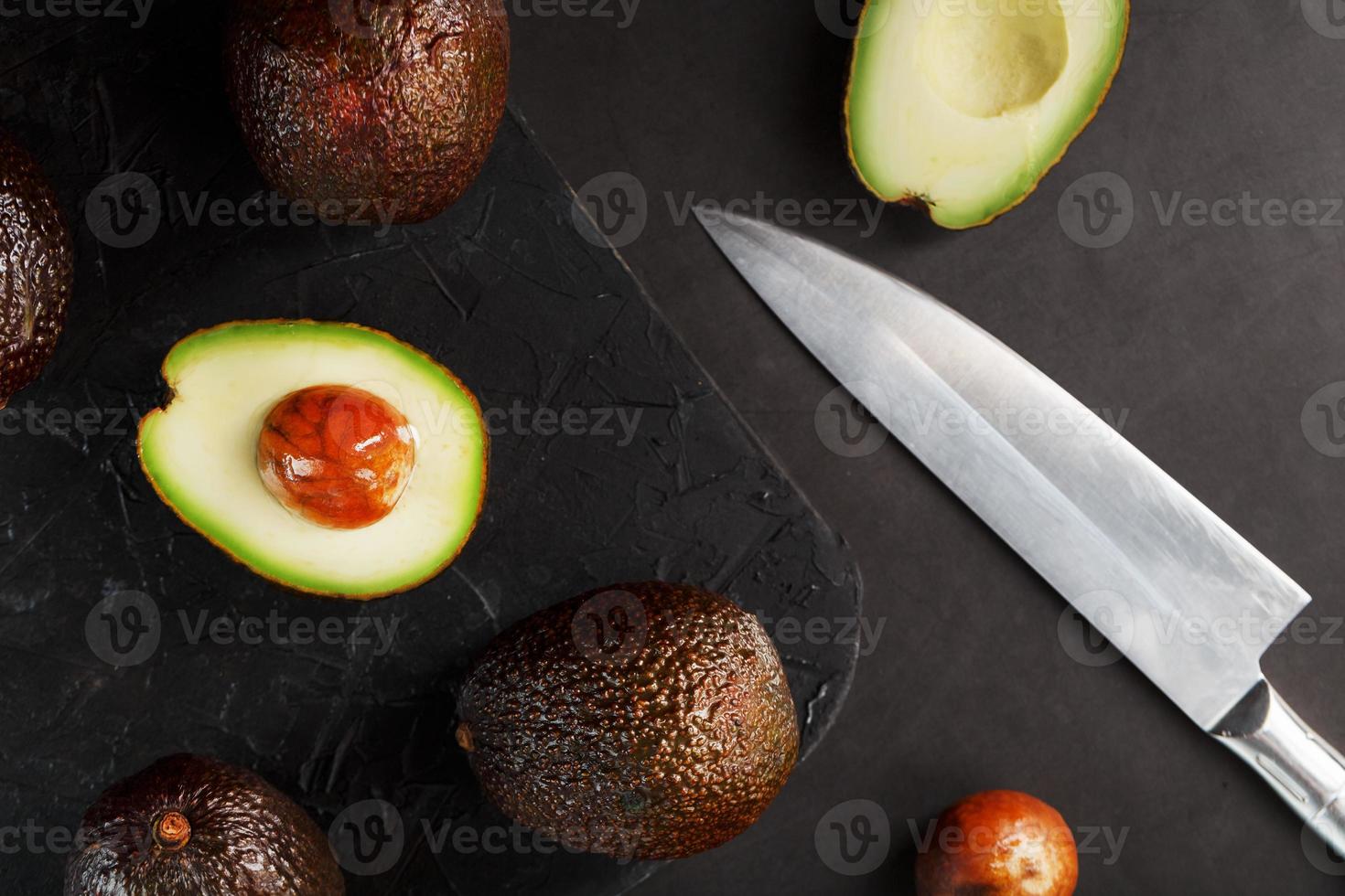 avocat bio tranché et entier avec un couteau sur fond noir. photo