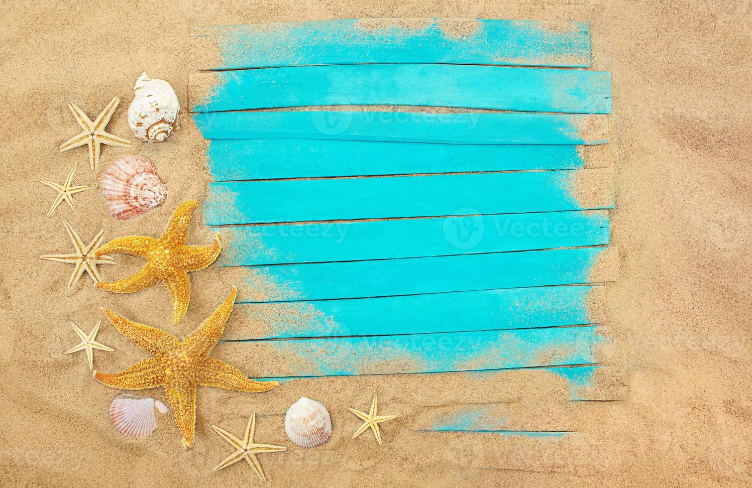 planches de bois bleues avec étoiles de mer, coquillages dans le sable. cadre d'été. concept de vacances, mer, voyage. copie espace photo