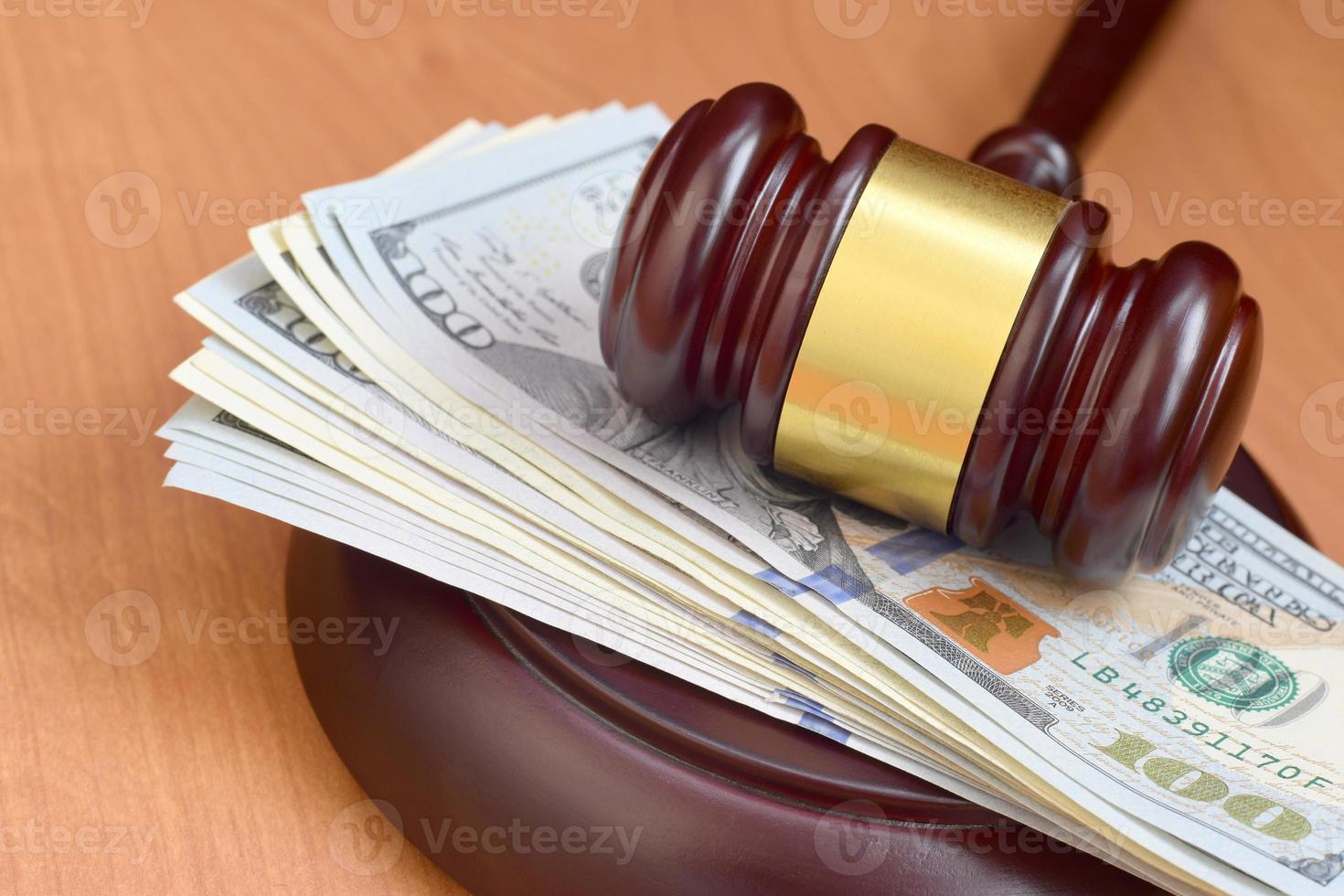 marteau de juge et argent sur une table en bois marron. plusieurs centaines de billets d'un dollar sous la malveillance du juge sur le bureau du tribunal. jugement et pot-de-vin photo