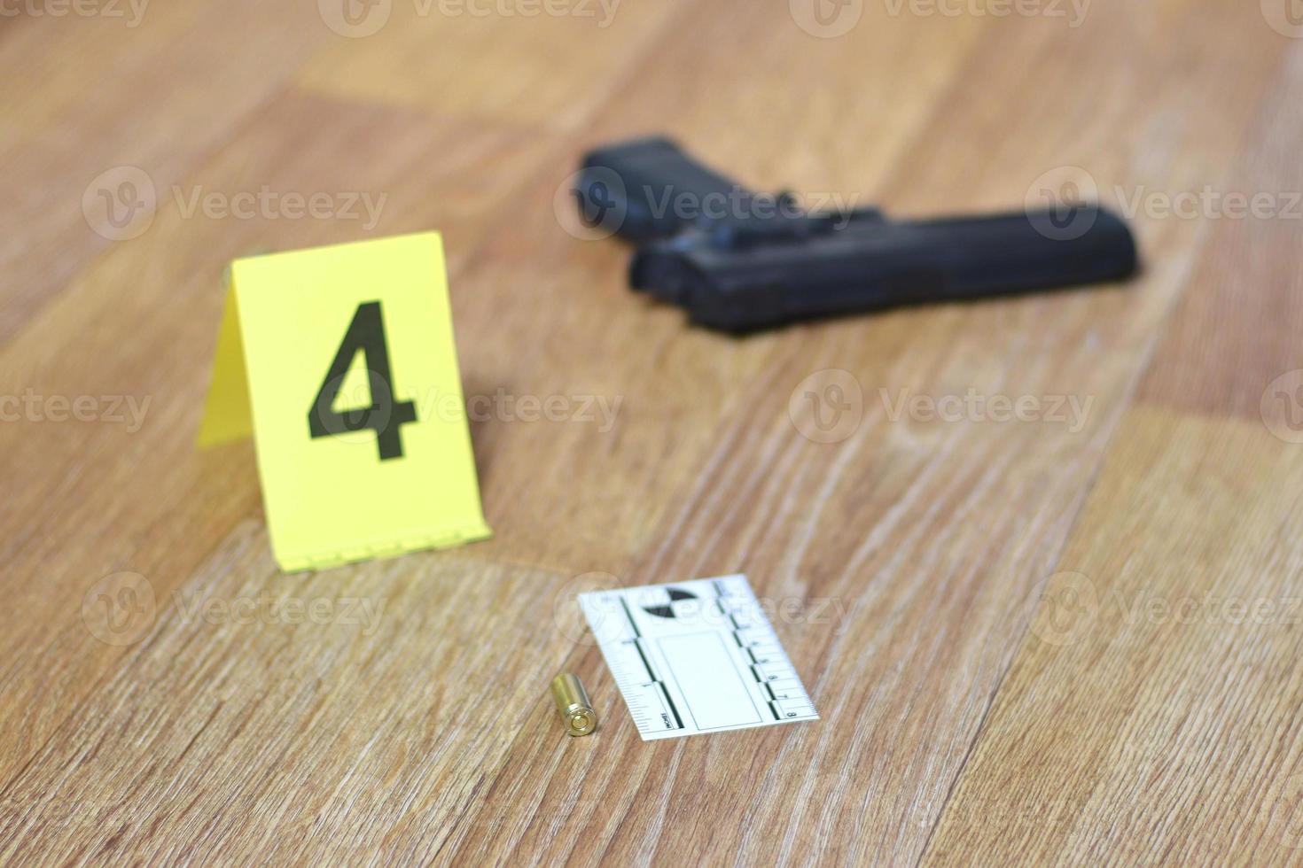 concept d'enquête sur les lieux du crime - pistolet et coquille de balle contre le marqueur de crime jaune sur le sol de l'appartement photo