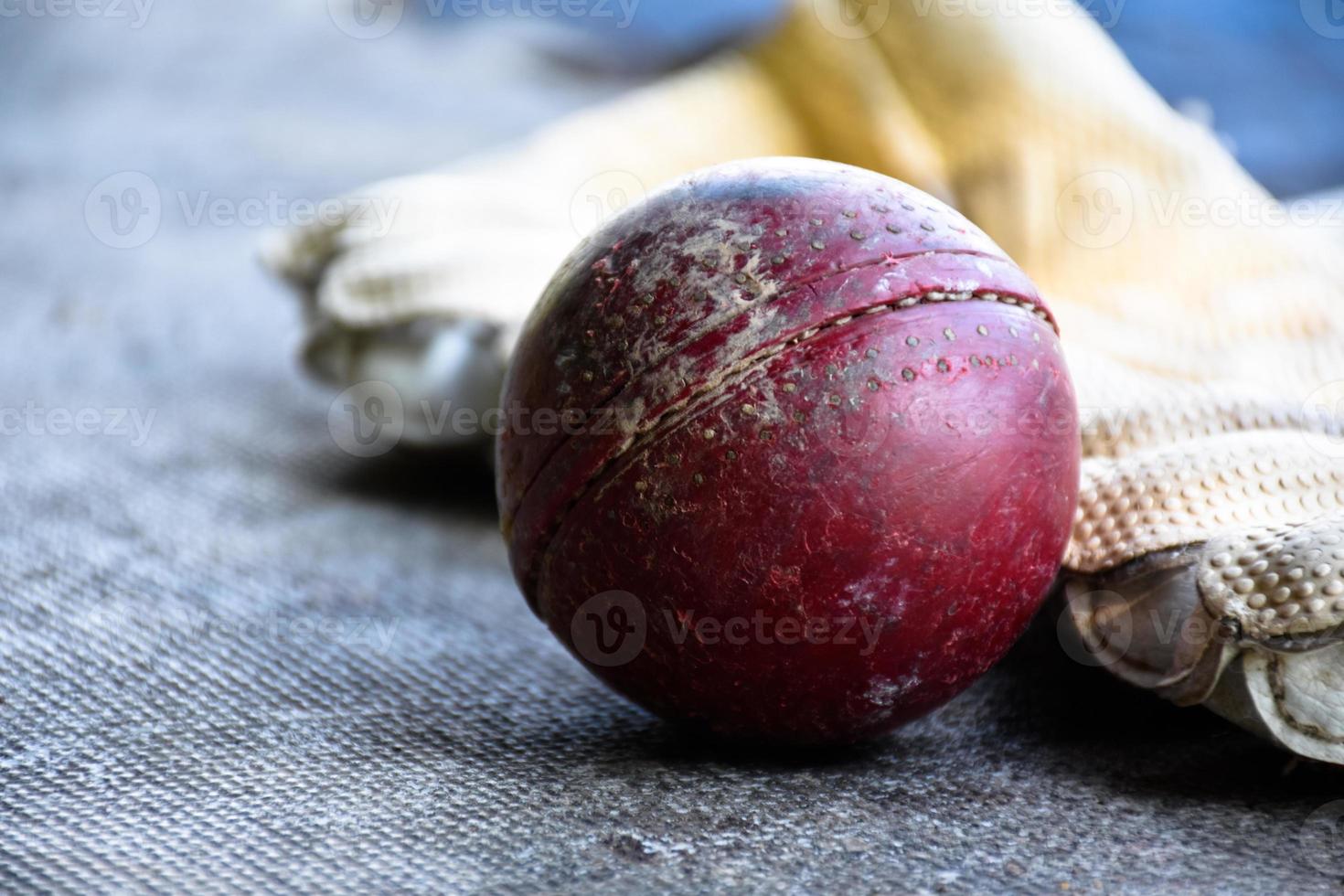 entraînement des équipements de sport de cricket au sol, ballon en cuir, gants et batte, mise au point douce et sélective sur le ballon. photo