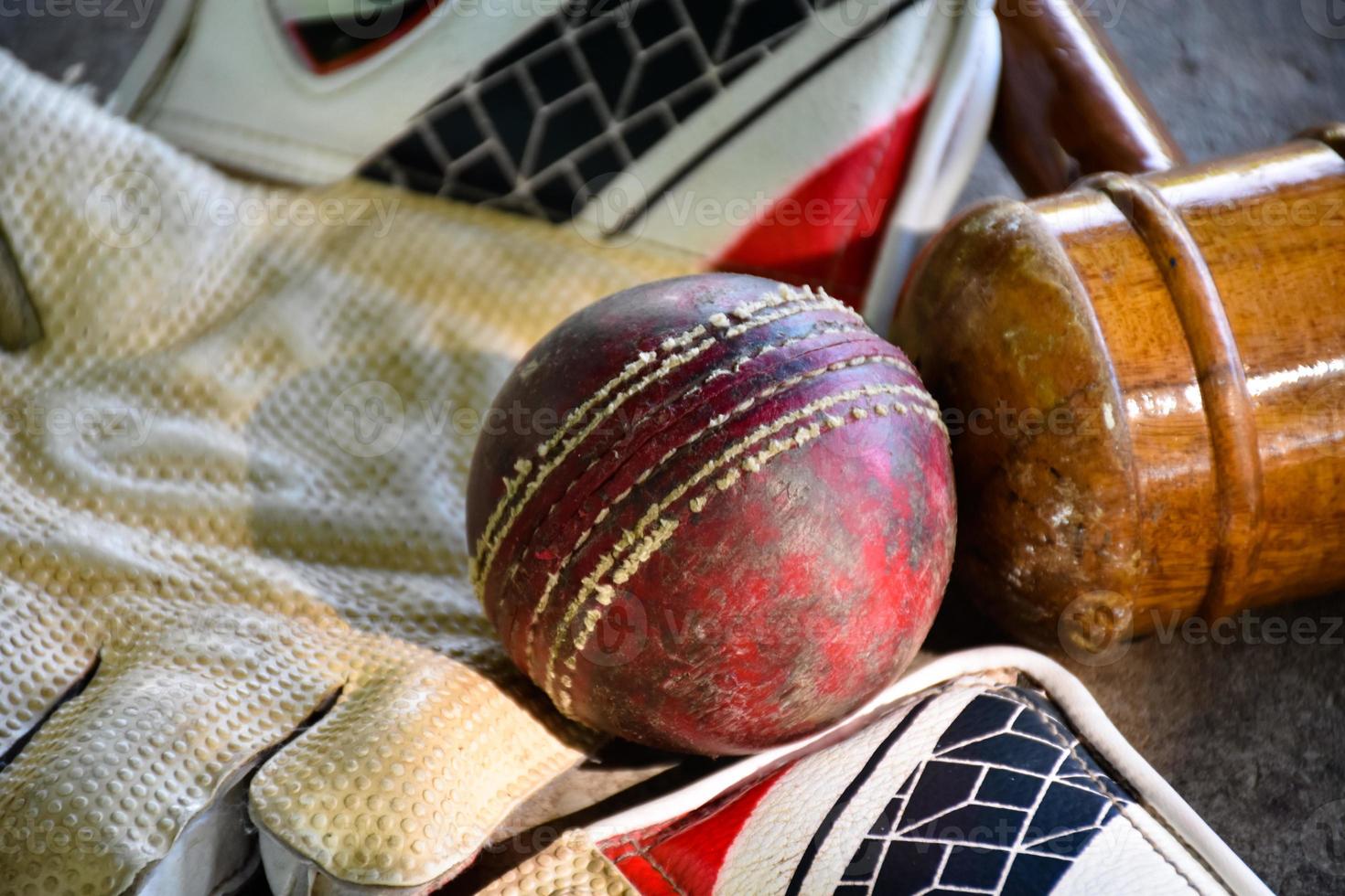 entraînement des équipements de sport de cricket au sol, ballon en cuir, gants et batte, mise au point douce et sélective sur le ballon. photo