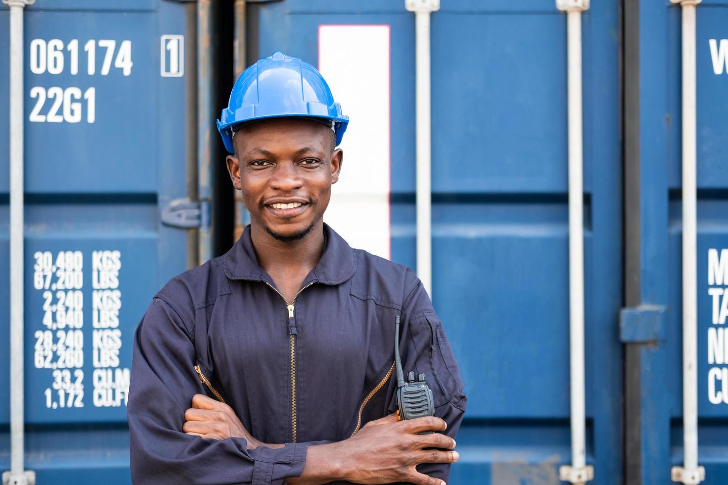 mise au point sélective sur le visage d'un travailleur logistique africain noir portant un équipement de sécurité, vérifier et inspecter l'état du conteneur tout en parlant et communiquer avec son équipe par appareil radio. photo