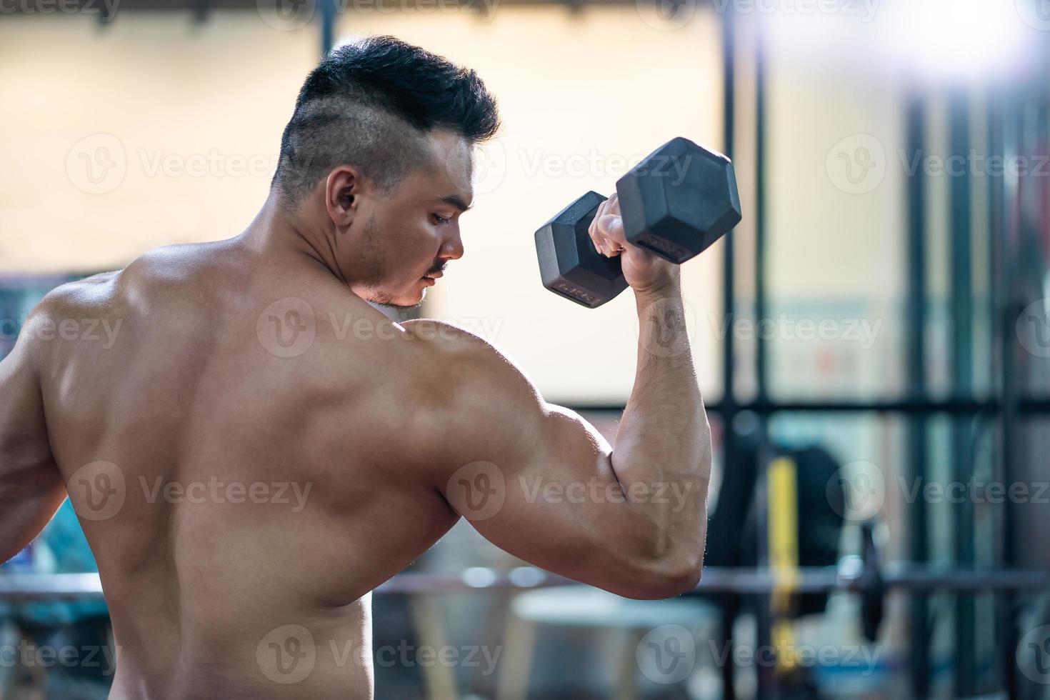 beaux hommes caucasiens adultes transpirant tout en soulevant l'entraînement d'haltères pour la partie musculaire du biceps du bras à l'intérieur de la salle de fitness. entraînement sportif d'athlète de musculation pour la force corporelle et une bonne santé. photo